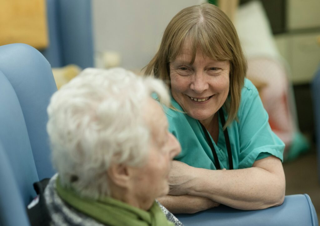 Carer in scrubs chatting with an older woman